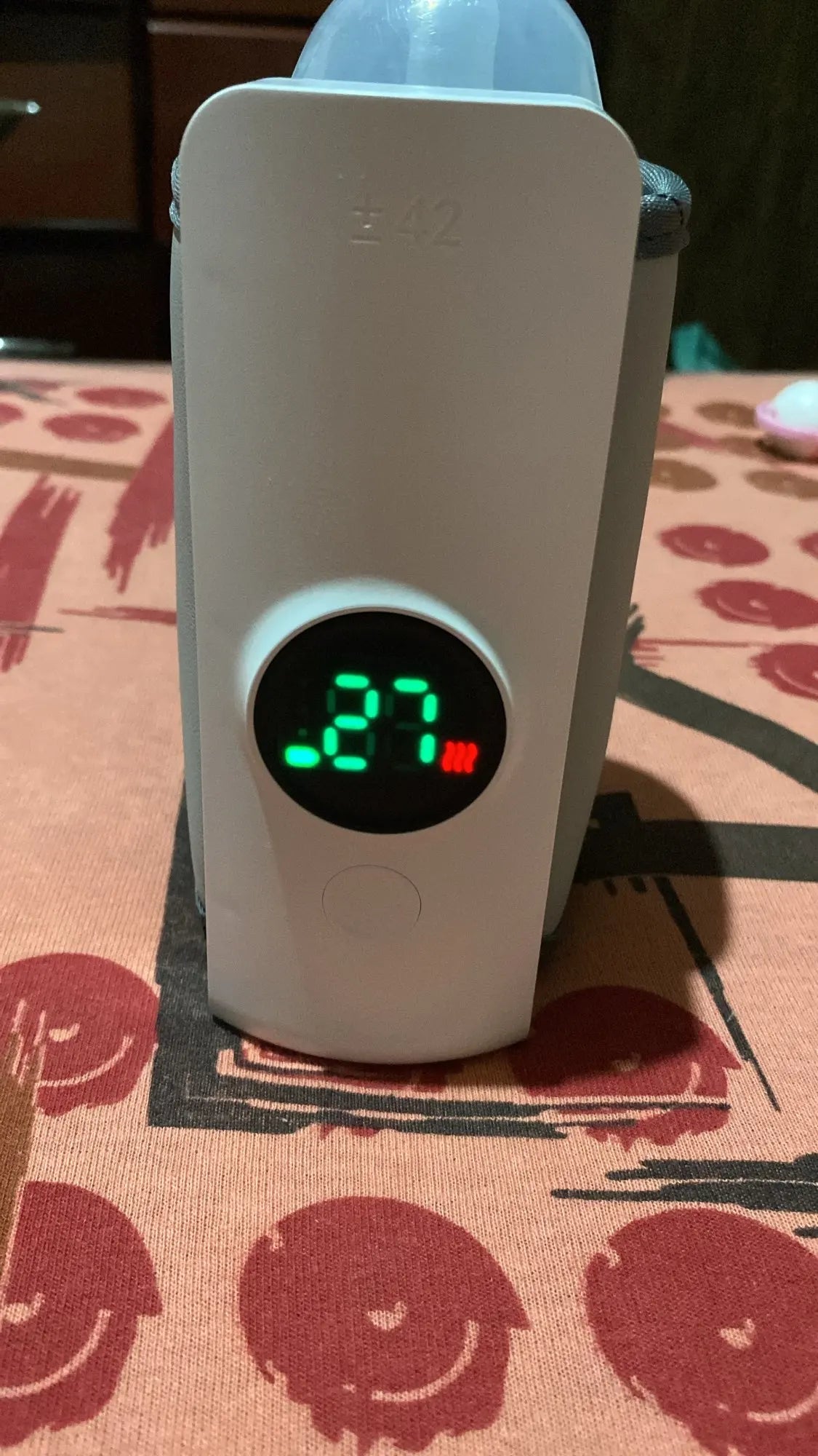 Digital thermometer displaying a temperature on a baby bottle warmer